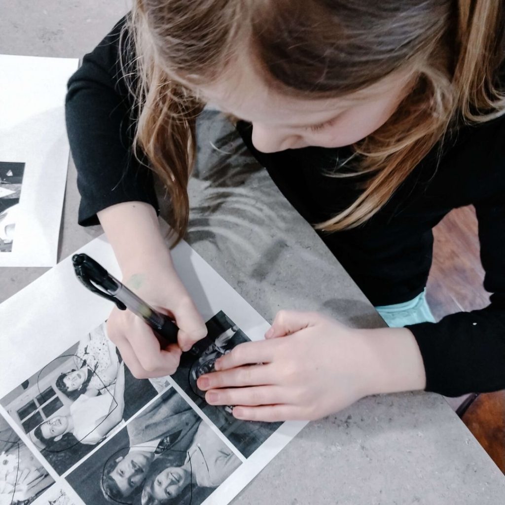 girl tracing heart outline on family photos